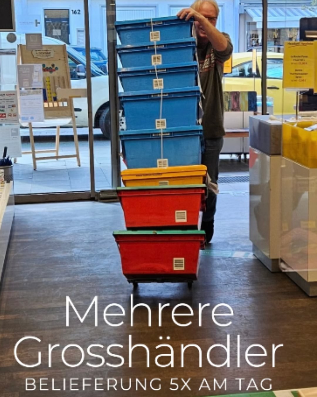 Mitarbeiter der Hausdorff Apotheke transportiert mehrere gestapelte Lieferkisten – die Apotheke wird mehrmals täglich von verschiedenen Großhändlern beliefert